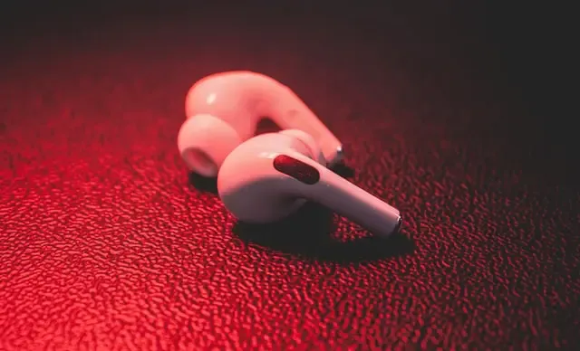 White wireless earbuds lying on a red textured surface
