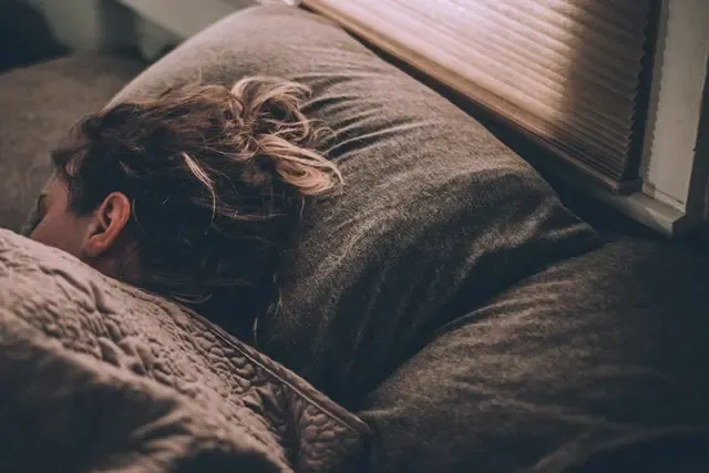 Person asleep on their side in a dim bedroom