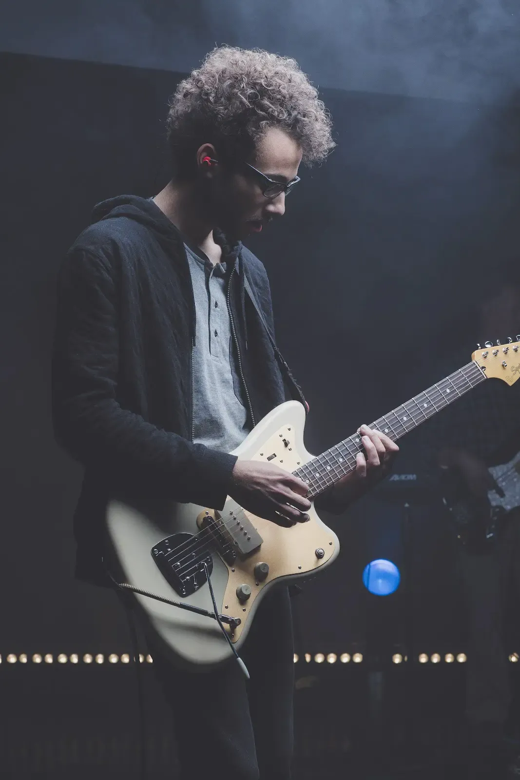 A guitarist wears in-ear monitors while performing on stage